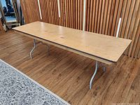 Top view of rectangular plywood folding table with steel folding legs extended