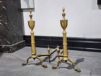 Front view of pair of brass andirons showing design details