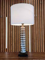 Full lamp with shade lit against wood slat wall
