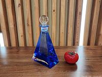 Full view of cobalt blue pyramid decanter beside red scale object