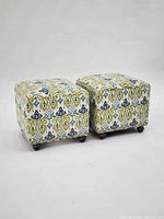 Pair of square patterned ottomans on casters, front three-quarter view