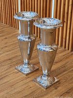 Pair of polished cast aluminum urn vases standing on wood floor