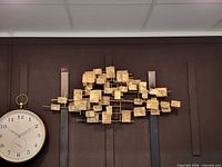 Front view of gold metal wall sculpture showing square panels and rods