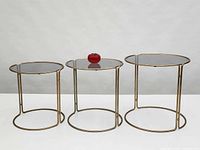 Front view of the three graduated brass nesting tables side by side