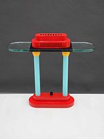Full view of red, turquoise and yellow Memphis style table lamp against neutral background