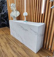Front and side view of white quartz table against slatted wood wall