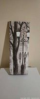 Front of canvas showing black-and-white street scene with tree, lamppost and figures