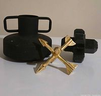 Front view of all three decor pieces: black two-handle vase, black cross sculpture, gold arrow star