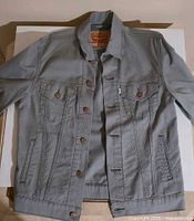 Front view of grey Levi's denim jacket, buttoned pockets and front detailing visible