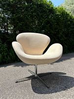 Front view of cream upholstered swivel lounge chair on chrome X-base