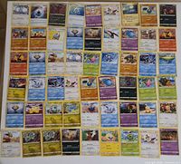 Roughly 50–60 assorted Pokémon creature/trainer cards laid out in rows