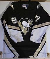Front view of black Penguins jersey showing logo and sleeve numbers