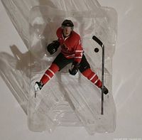 Front view of Sidney Crosby action figure in red jersey within blister tray, stick positioned right side
