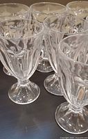Seven stemmed glass dishes grouped together showing bee motif and pedestal bases