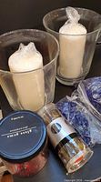 Two glass holders with wrapped pillar candles, jar of red gems, tube of tealights, blue gems in bags