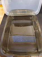 Open view of tinted glass dish showing interior and side handles, lid propped open