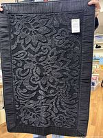 Full view of black floral bathmat held vertically