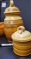 large and small striped lidded pottery canisters with sharpie for scale
