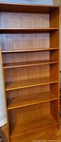 front view of tall teak veneer bookshelf with five shelves