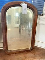 Front view of arched wood frame mirror with visible wear and clouded glass