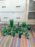 All 18 emerald green glass pieces displayed on rug