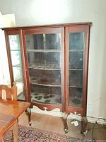 Front view of mahogany china cabinet showing glass doors, shelves, legs