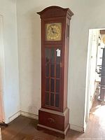 Full view of tall mahogany grandfather clock against wall