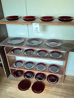 Shelves holding multiple red glass plates of varying depth