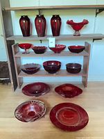 Group view of all red glass pieces on shelves and floor