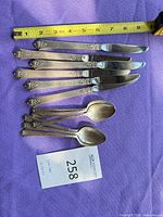 Overview of 4 knives and 4 spoons with measuring tape