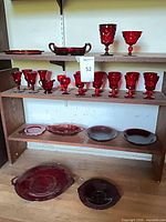 Shelved display of ruby red glassware including goblets, plates, serving pieces