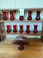 Shelf with ten matching ruby red glass vases, five on each of two shelves