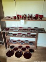 Overall view of shelving with ruby red glass plates, bowls, goblets, vases, shakers, candle holders
