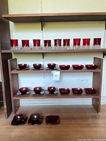 Full shelving view showing tumblers on upper shelf, cups with saucers on middle shelves, additional saucers on lower shelves
