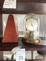 Schatz anniversary clock with glass dome next to wooden metronome