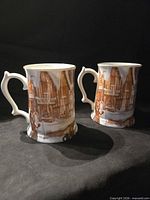 Front view of both mugs showing skating scene and handles