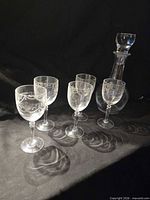 Front view of crystal decanter with stopper and four stemmed glasses