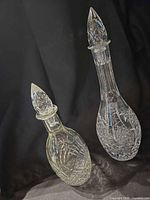Two crystal decanters side by side on dark backdrop