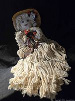 Full view of mop doll showing body, face, hat, embellishments
