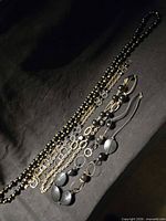 Four black and gold-tone necklaces laid out on dark cloth