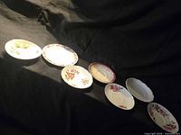 Seven small floral and patterned plates displayed side-by-side