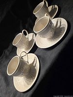 Overhead view of four cups on saucers displaying matching pattern