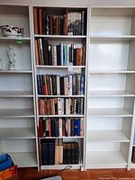 Overall view of centre bookcase with six filled shelves flanked by empty units