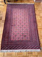 Full view of the burgundy Bokhara-style rug with fringe