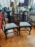 Front view of both black wooden armchairs with patterned seats