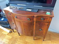 Front view of serpentine wood dresser with drawers and cupboard doors