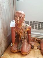 Front view of painted wooden kneeling figure statue