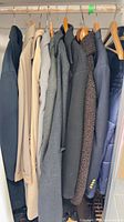 Nine men’s coats and blazers hanging on rod