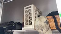 Top shelf with backpack, plastic crate, wicker basket, baseball cap