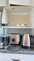 Overview of all four appliances on countertop: blender, toaster, kettle, immersion blender